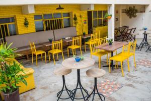 a restaurant with yellow chairs and tables and tables and chairs at Flor de Lis Hostel in Viçosa