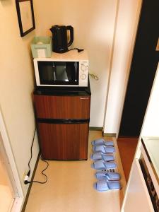 Un four micro-ondes est installé au-dessus d'une armoire en bois. dans l'établissement Joinus Ise Apartment, à Ise