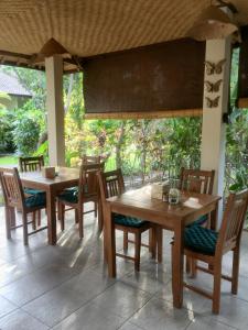 a dining area with wooden tables and chairs at Mango Moon in Pemuteran