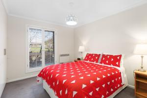 a red bed in a white room with a window at City One Apartment in Mount Gambier