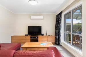 a living room with a couch and a tv and a window at City One Apartment in Mount Gambier