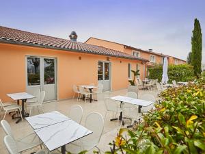 un patio avec des tables et des chaises et un bâtiment dans l'établissement Kyriad Direct Bron Lyon Eurexpo, à Bron