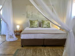 a bedroom with a bed with a canopy at Musica do Mar Beach Front Apartments, Garden View in Praia do Tofo