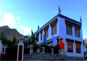 a white building with flags in front of it at Hotel Mahay Palace in Leh