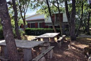 una mesa de picnic y bancos frente a un edificio en Conca Marina, en Tempio Pausania