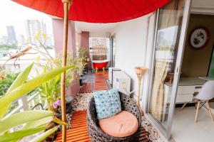 a balcony with a chair and an umbrella at Baan Sabai Rama IV Apartment in Bangkok