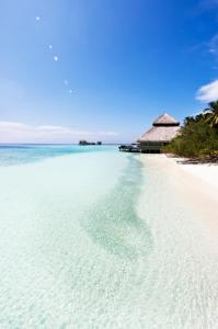 a beach with clear water and a building at Adaaran Club Rannalhi - All Inclusive - 45 Minutes away from Male by Speedboat in South Male Atoll