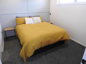 um quarto com uma cama com um cobertor amarelo em The Loft Apartments em Westport