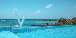 a swimming pool with a view of the ocean and boats at Ocean V Hotel in Pereybere
