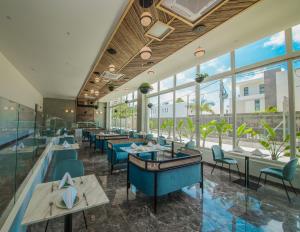 um restaurante com cadeiras e mesas azuis e janelas em Ocean V Hotel em Pereybere