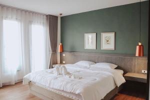 1 cama grande en un dormitorio con una pared verde en Chula Premium Homes, en Ban Chang