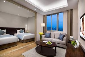 Somerset Emerald City Suzhou في سوتشو: غرفه فندقيه بسرير واريكه