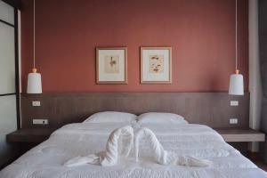 1 dormitorio con cama blanca y pared roja en Chula Premium Homes, en Ban Chang