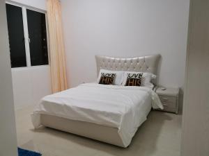 a white bedroom with a white bed with two pillows at Cozy 3 Bedrooms Apartment Langkawi in Kuah