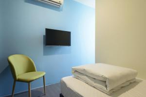 嘉義市的住宿－客旅家青年旅館 Travelers Plus，配有床、椅子和电视的房间