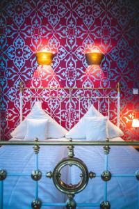 a bed with white pillows and a red wall at Hotel Alexander in Wiesbaden