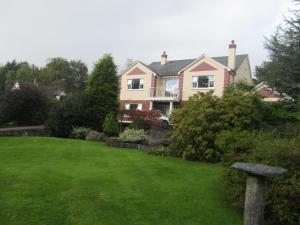 Una casa con un césped verde delante de ella. en Neidin House, en Kenmare