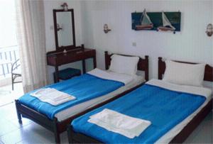 a bedroom with two beds with blue sheets and a mirror at Helios Hotel in Agia Marina Aegina +12 photos