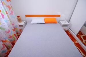 a small bedroom with a bed with an orange pillow at Apartment Jony Lux Center in Zlatibor