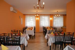 Un comedor con mesas y sillas y una lámpara de araña. en Hostel Ferihegy, en Vecsés