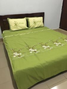 a green bed with a green comforter with flowers on it at Nhà Nghỉ THẢO NGUYÊN XANH in Buon Ma Thuot +25 photos
