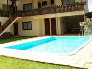 a swimming pool in front of a house at Pousada Adler in Treze Tílias