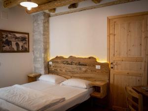 a bedroom with two beds and a wooden headboard at Locanda Ponte Serra in Lamon