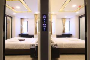 two beds in a room with two mirrors at Pratunam Atrium Hotel in Bangkok