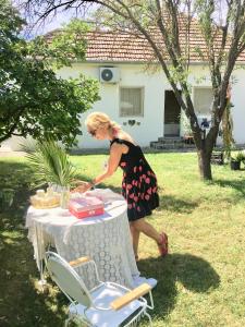 a woman standing next to a table with at Casa Bella & Nova in Palić