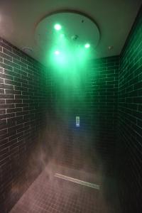 La salle de bains est pourvue d'une lumière verte sur un mur en briques. dans l'établissement Kyriad Hotel Dijon Gare, à Dijon