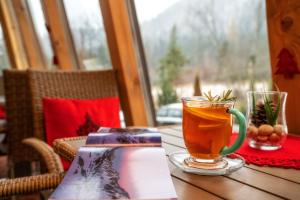 a cup of tea sitting on a table with a book at Hotel Eco Tatry Holiday& Spa in Kościelisko