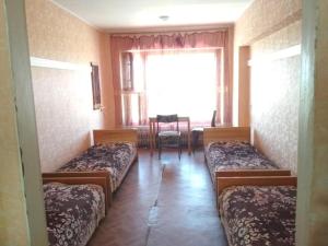 um quarto com três camas e uma mesa e uma janela em Готель на Автовокзалі em Poltava