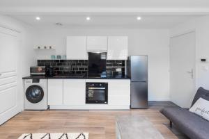 uma cozinha com armários brancos e electrodomésticos pretos em Bienvenue à Reims type studio charmant et lumineux 2eme étage em Reims