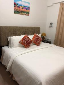 a large white bed with two pillows on it at Kerteh Apartment in Kertih +45 photos