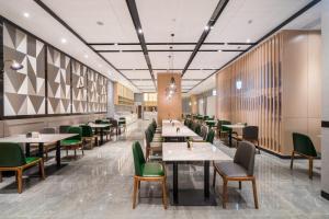 a dining room with tables and green chairs at Atour Hotel Changsha Lugu Branch in Changsha