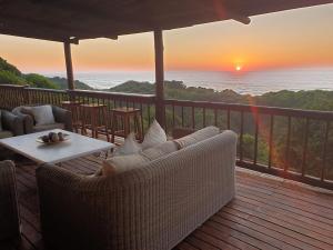 a porch with a couch and a table with a sunset at Kangela 11 in Ponta Malongane