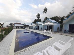 a villa with a swimming pool and white chairs at CC Beach Resort in Khanom