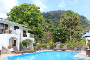 una piscina frente a una casa con sillas y árboles en Sun Properties and Resort Hotel en Beau Vallon