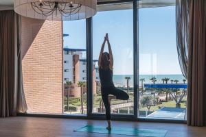 a woman doing a yoga pose in front of a window at Almar Jesolo Resort & Spa in Lido di Jesolo