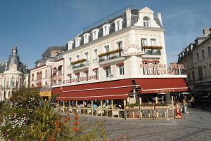 a building with a restaurant in front of it at Hotel Le Central in Trouville-sur-Mer