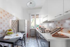 a white kitchen with a table and a refrigerator at Casa Sibilla in Ferrara