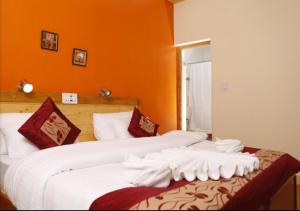 2 Betten in einem Zimmer mit orangefarbenen Wänden in der Unterkunft Royal Heritage Resort in Leh