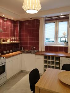cocina con armarios blancos y paredes de azulejos rojos en Apartament pod Jaworzyną, en Krynica-Zdrój