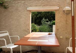 una mesa de madera en un patio con 2 sillas en Paradix holiday apartment - gîte 3, 2 pers, en Nissan-lez-Enserune