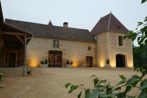 un grand bâtiment en pierre avec une grande cour dans l'établissement Chambres d'hôtes Les Peyrouses, à Sarlat-la-Canéda