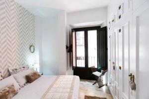 a white bedroom with a bed and a window at Cheap & Chic in the center of Sevilla in Seville