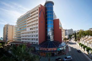 un edificio alto con un poste azul en una ciudad en Pierre & Vacances Benalmádena Príncipe, en Benalmádena