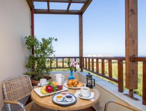 una mesa con comida en el balcón con vistas al océano en ERIA RESORT for people with special abilities, en Máleme