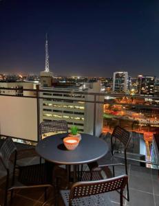 een tafel en stoelen op een balkon met een skyline van de stad bij LOCATION LOCATION CITY VIEWS NETFLIX WIFI WINE in Perth