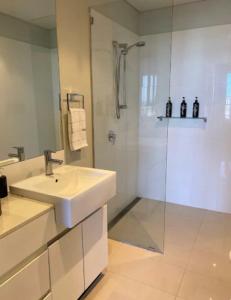 een witte badkamer met een wastafel en een douche bij LOCATION LOCATION CITY VIEWS NETFLIX WIFI WINE in Perth